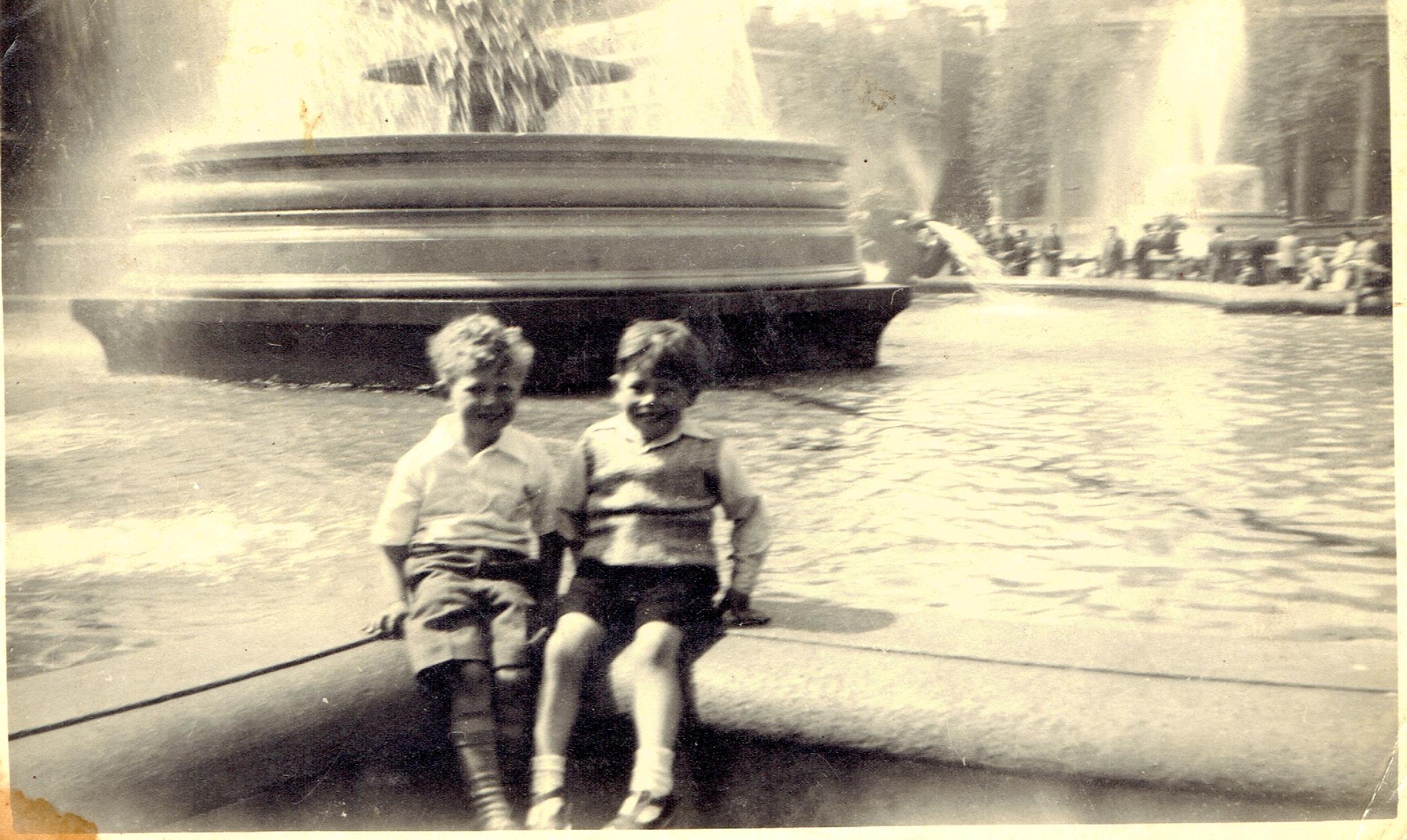 Two children sitting on the edge of the fountain at Trafalgar Square