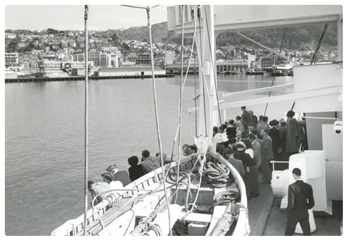 Ten Pound Poms entering Wellington Harbour in the 1950's. Peple crowded in the bow of the boat as it arrive.