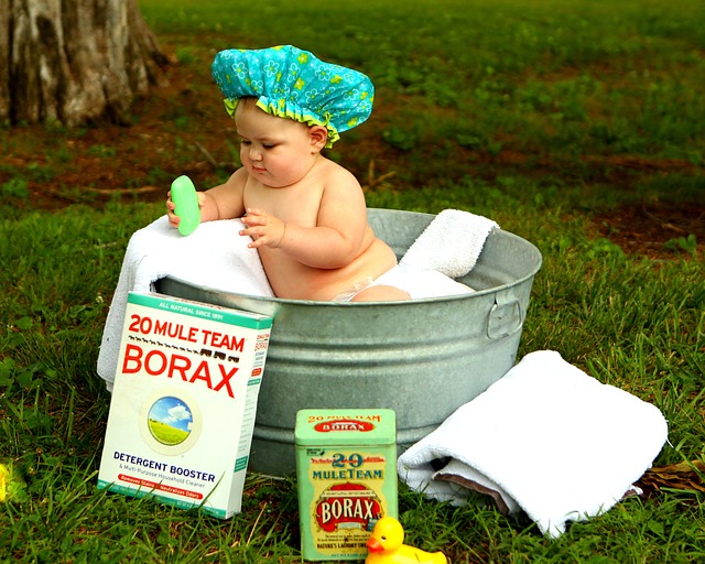A photograph of a small child in an old tin bath. Child holding soap.
